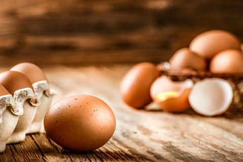 Eggs in a carton with broken eggs in the background