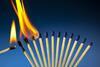 An image showing a row of closely positioned matches burning one by one in a domino effect fashion