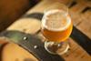 An image showing a glass of beer on top of a barrel