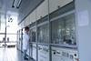 An image showing a male scientist writing with a sharpie on a fumehood sash inside a clean laboratory