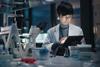 A scientist uses a tablet at a desk in a laboratory