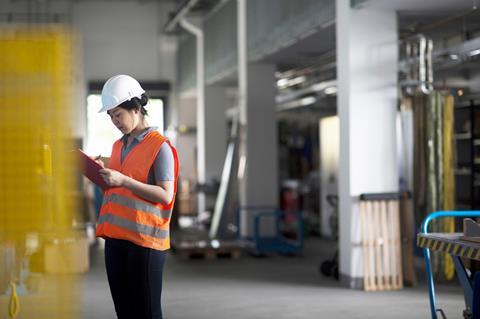 An inspector wearing PPE checking a manufacturing environrment