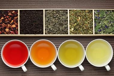 Looking down on four tea cups containing different kinds of tea, as well as the corresponding ingredients in containers