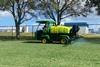 Landscapers using a small spraying vehicle to spray an area of grass