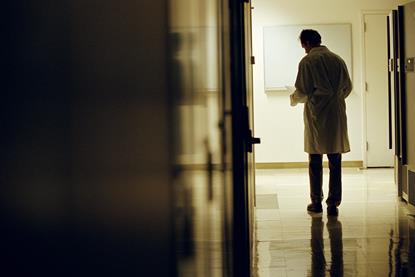 Rear view of a man in a lab coat on an empty corridor