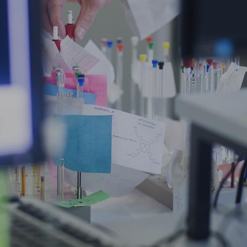 A scientist selects NMR tubes from a rack in a lab