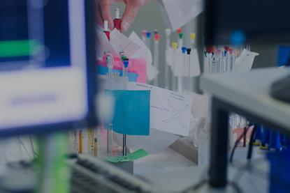 A scientist selects NMR tubes from a rack in a lab