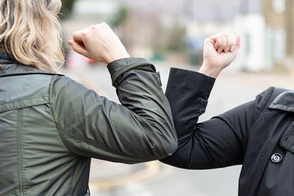 To avoid hand-to-hand contact during the coronavirus pandemic, two people bump elbows as a greeting